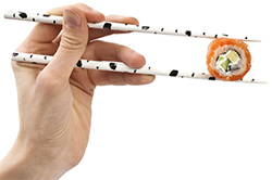 Рука палочками держит суши